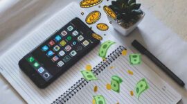 Membuka hp di atas buku (pexels)