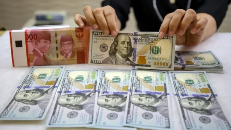 Karyawan memperlihatkan uang Rupiah dan Dolar AS di salah satu tempat penukaran uang asing di Jakarta, Senin (20/10/2025). (Bisnis)