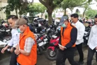 Varial Adhi Putra (belakang berjaket oranye) saat digiring petugas bersama satu tersangka lainnya.